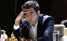 Vladimir kramnik pensando con una mano en la frente y de bajo un tablero de ajedrez